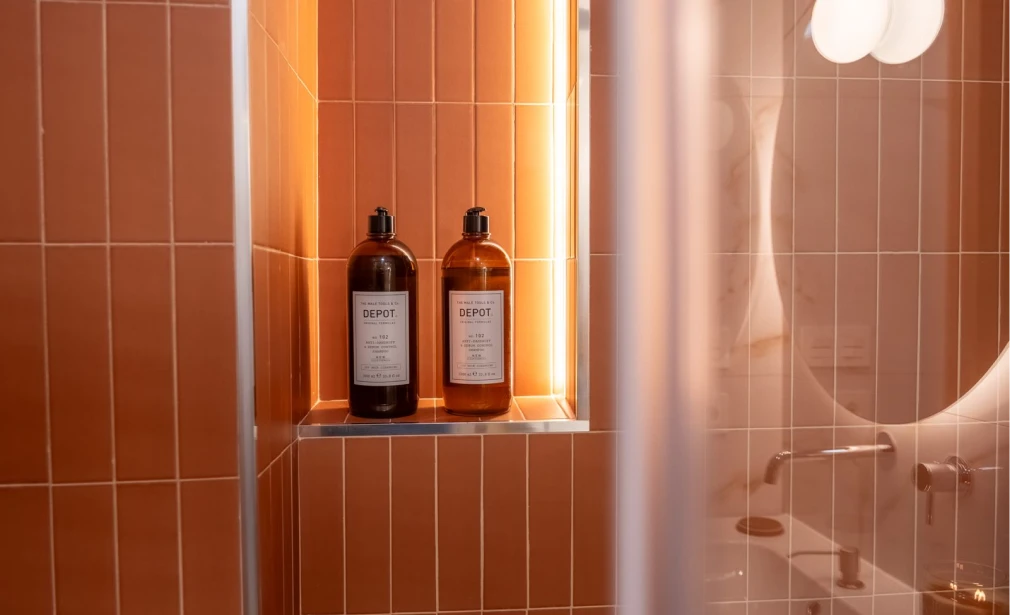 Detalle del baño de Casa 7G con azulejo terracota, nicho iluminado y espejo retroiluminado