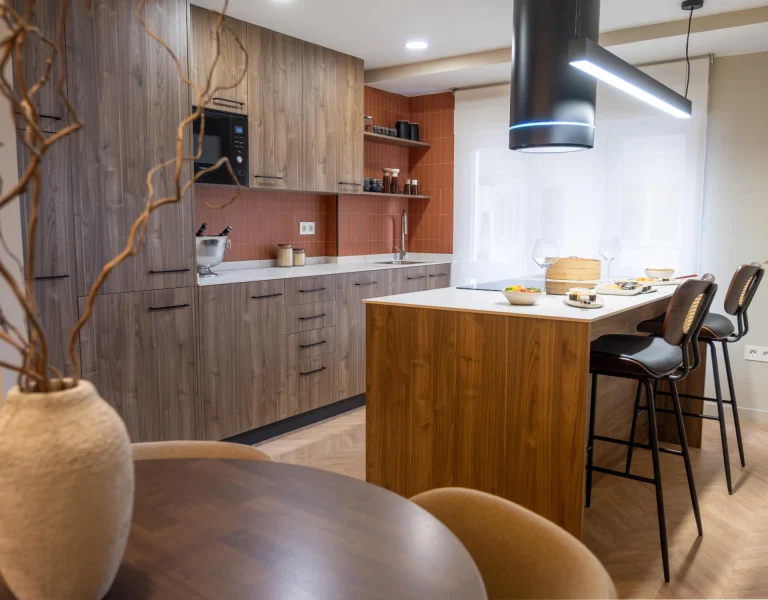 Interior de Casa 7G con cocina abierta, isla central, mobiliario en madera y lámpara suspendida