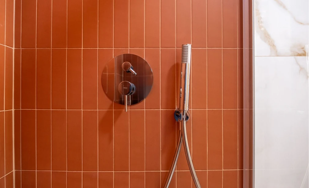 Detalle de la ducha de Casa 7G con azulejo terracota, grifería empotrada y mampara de vidrio