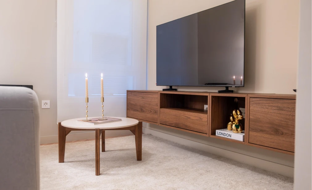 Interior de Casa 7G con salón cálido, mesa auxiliar redonda y mueble de televisión suspendido en madera