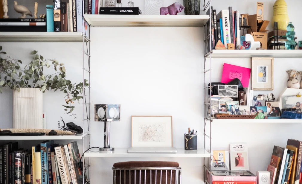 Interior de Casa M3 con escritorio integrado entre estanterías abiertas, libros, objetos decorativos y fotografías personales